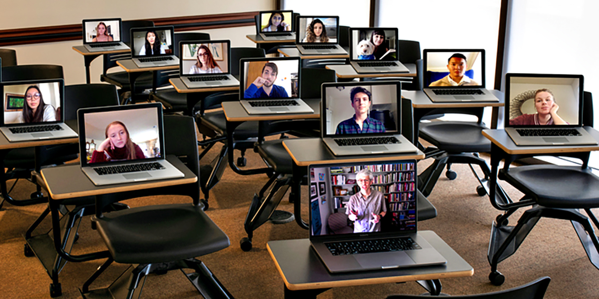 A classroom full of desks with open laptops stream students attending a virtual session.