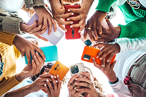 A circle of students working on their cell phones, shot from the ground up