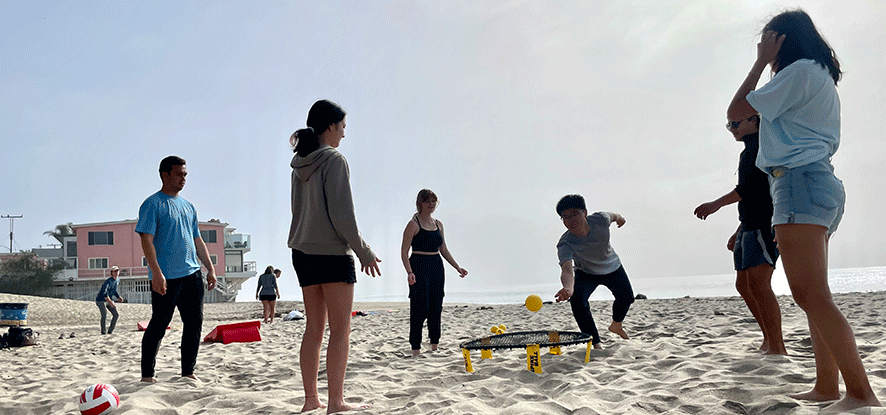 Students playing spike ball on the beach
