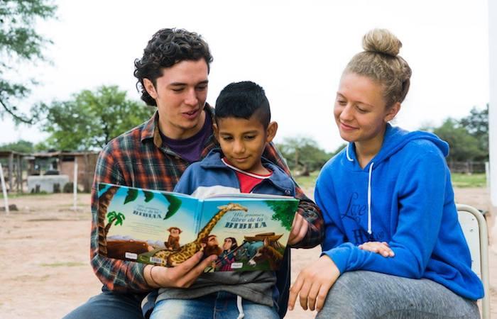 students reading book to a child