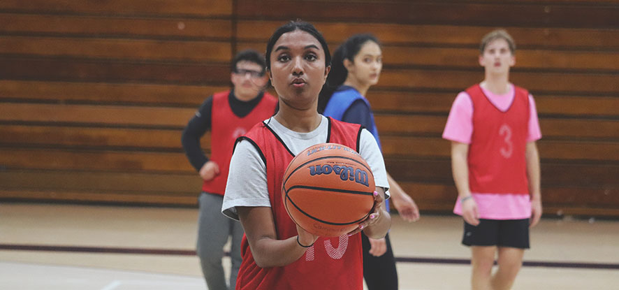 Female student holding basketball, getting ready to shoot the ball