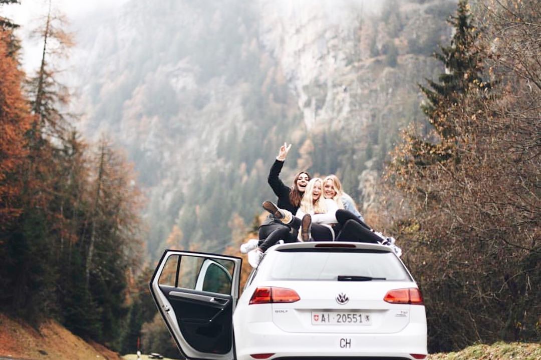 three girls pose on their car while studying abroad