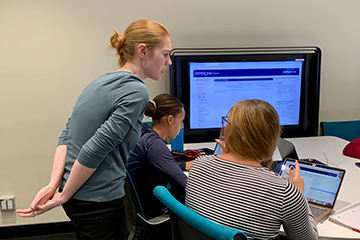Three students in the library work together on a project